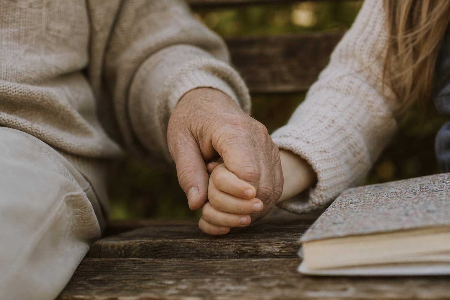 Großmutter hält die Hand ihres Enkelkindes auf einer Gartenbank